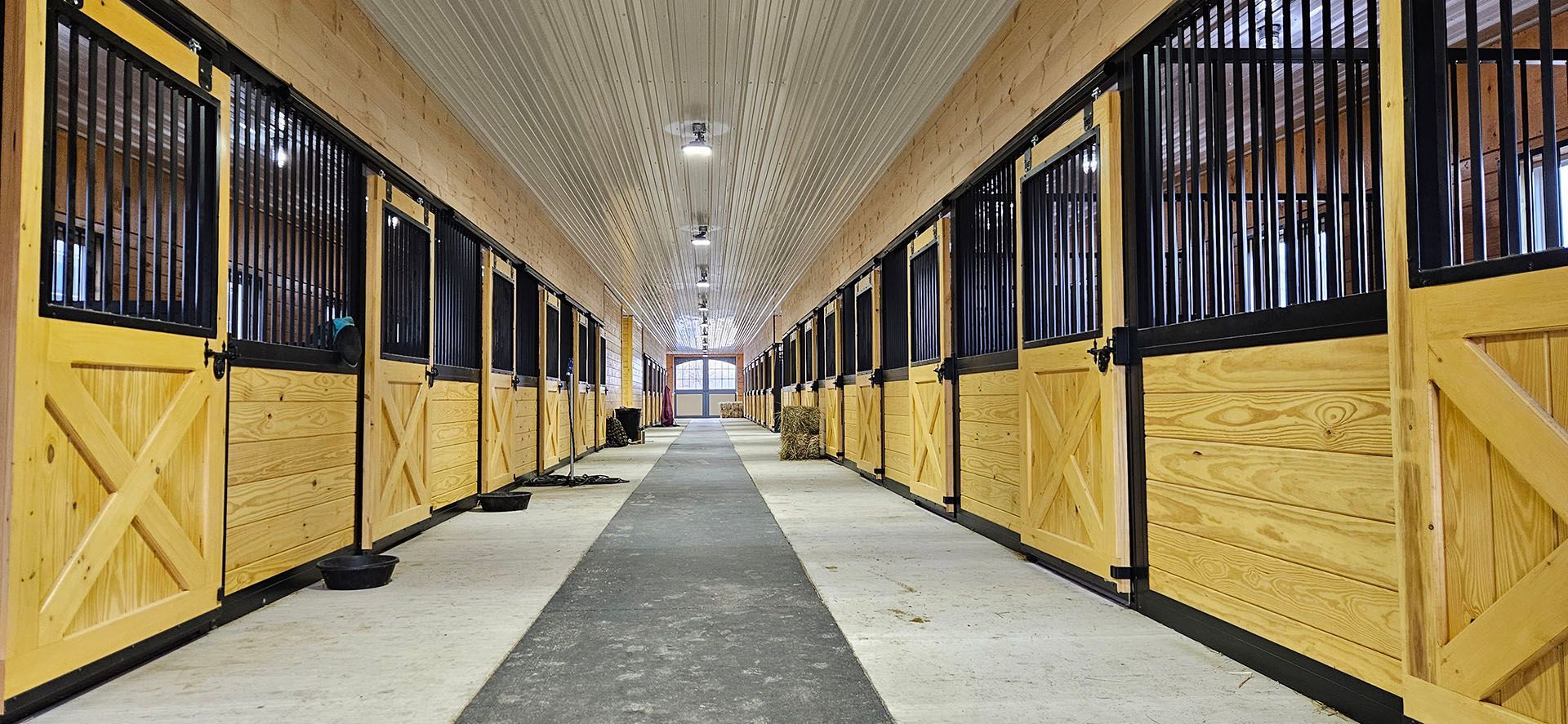 A long hallway filled with rows of wooden horse stables.