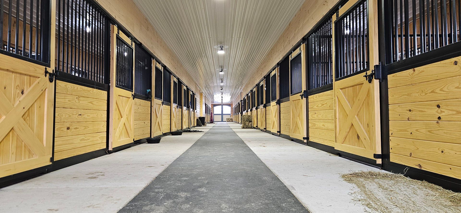 A long hallway filled with wooden stable doors and a gray carpet.