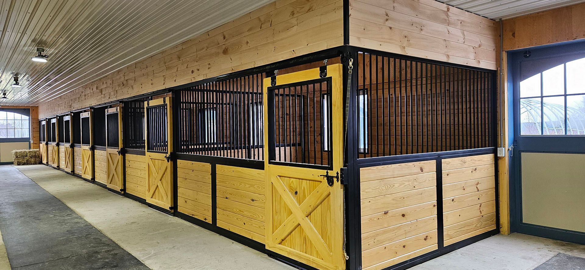 A row of wooden horse stalls with yellow doors in a barn.