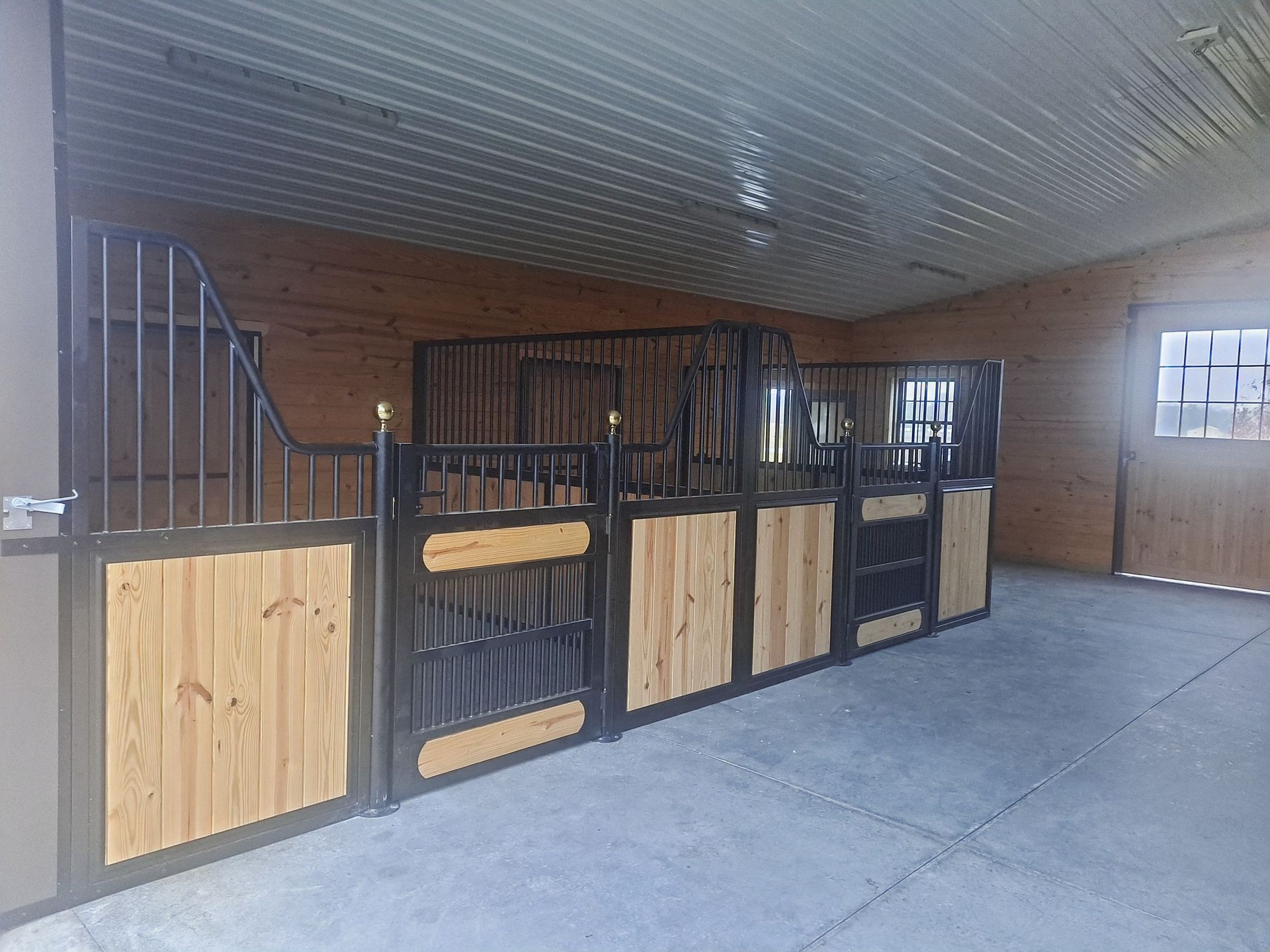 A horse stable with wooden stalls and a concrete floor.