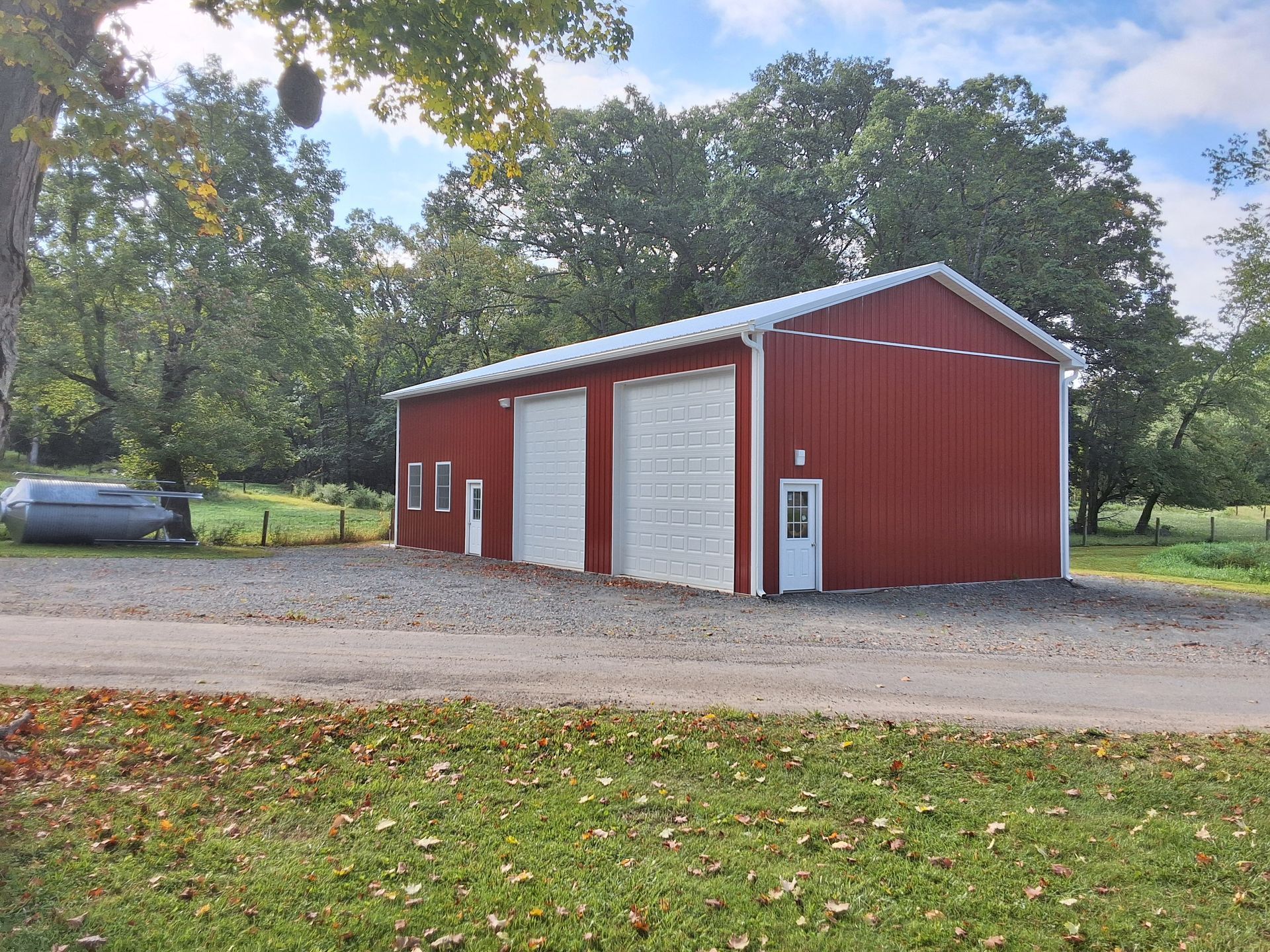 A red barn with white doors is in the middle of a grassy field.