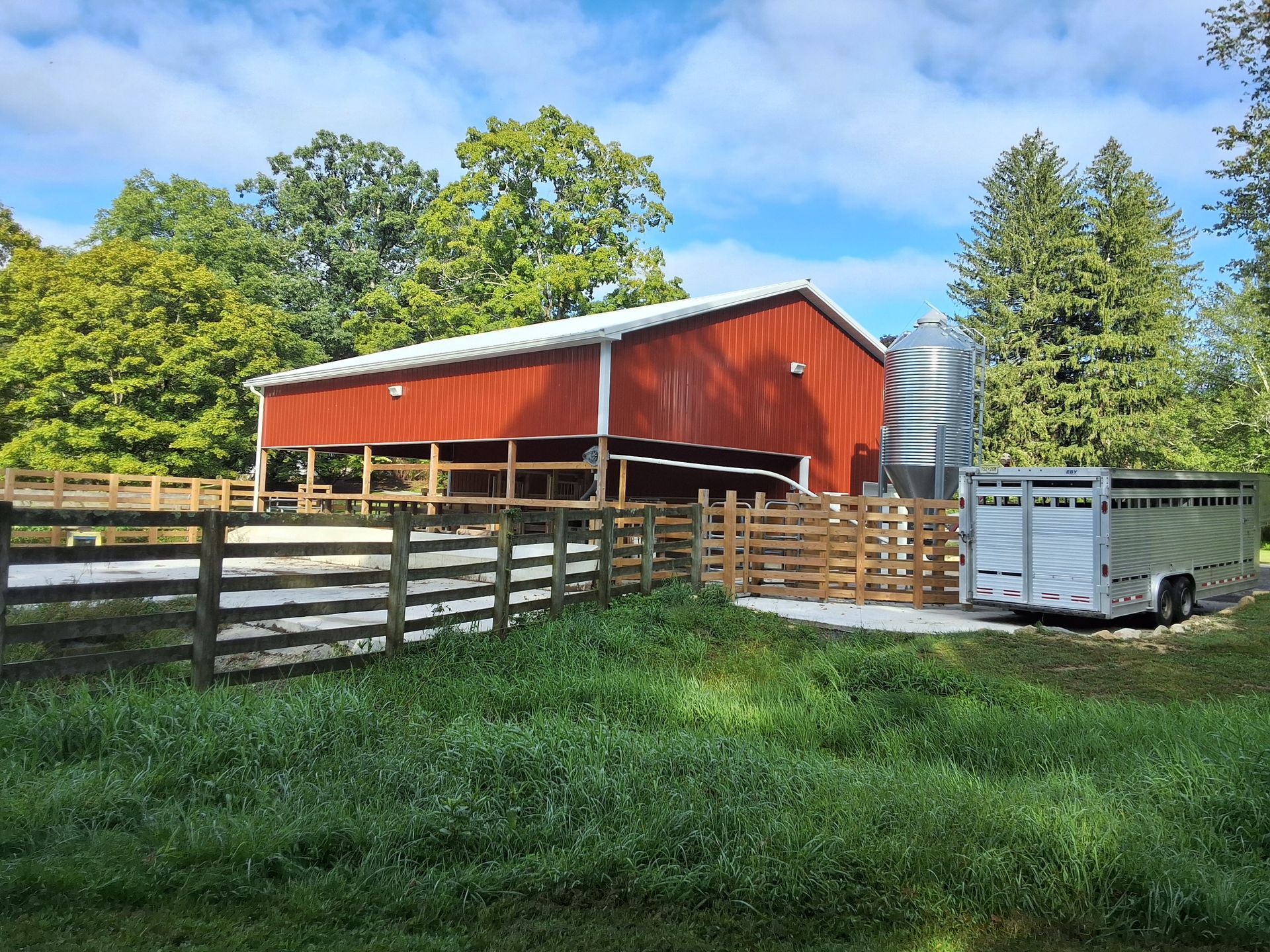 A red barn with a white trailer parked in front of it
