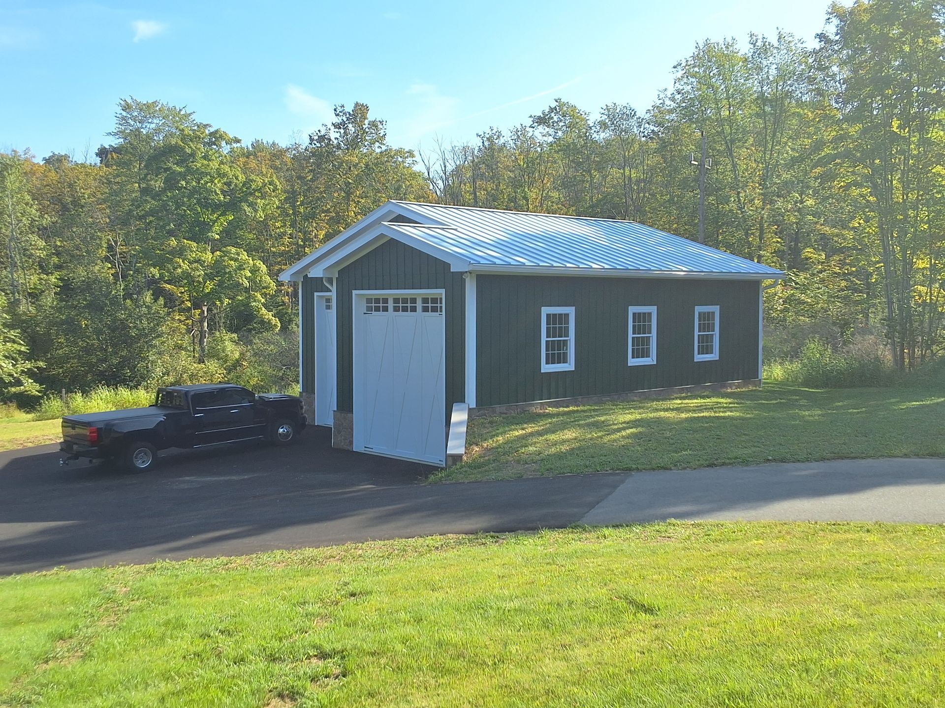 A red barn with white doors is in the middle of a grassy field