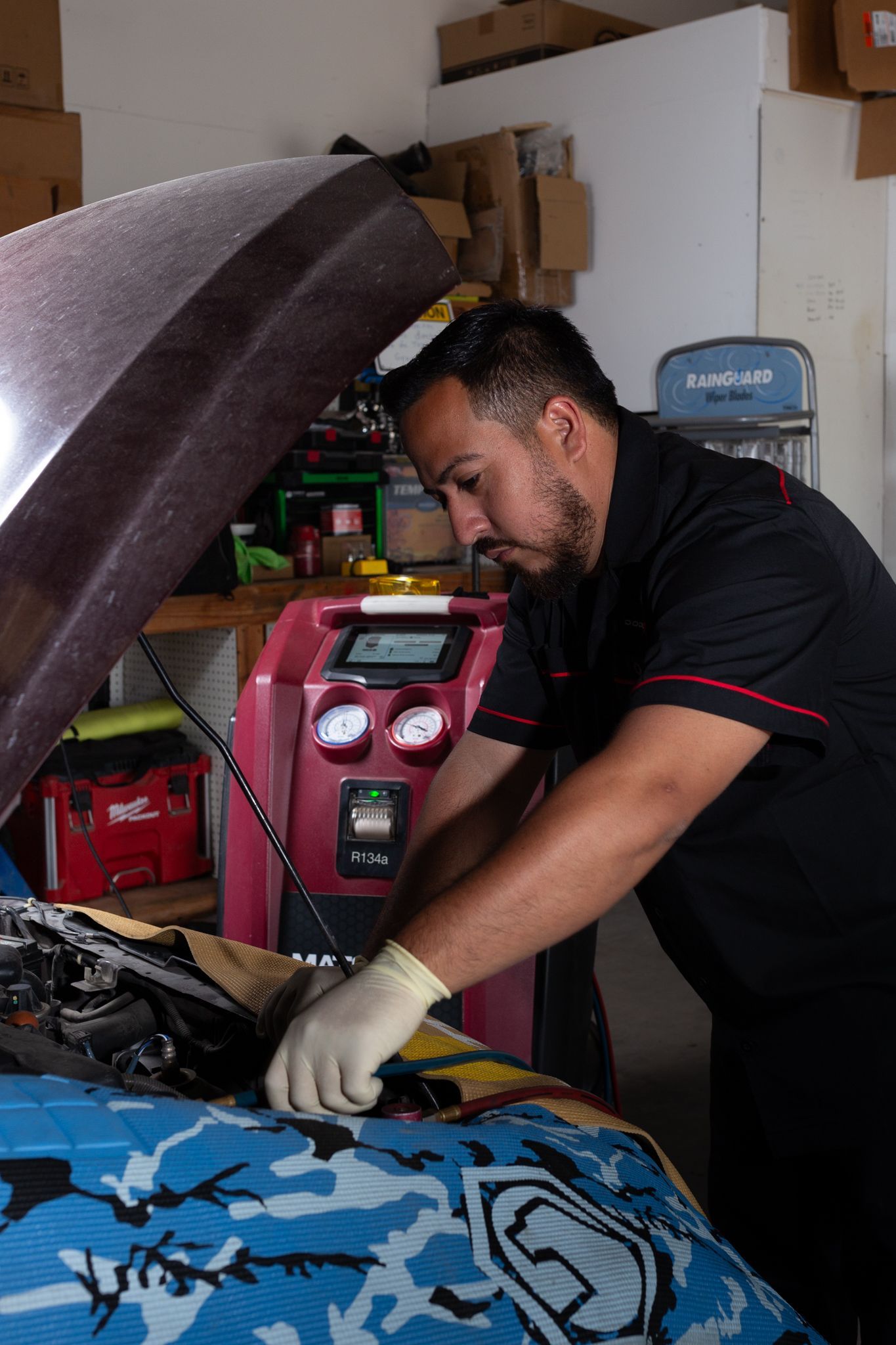 Mechanic working on a car engine with a diagnostic machine in a garage.