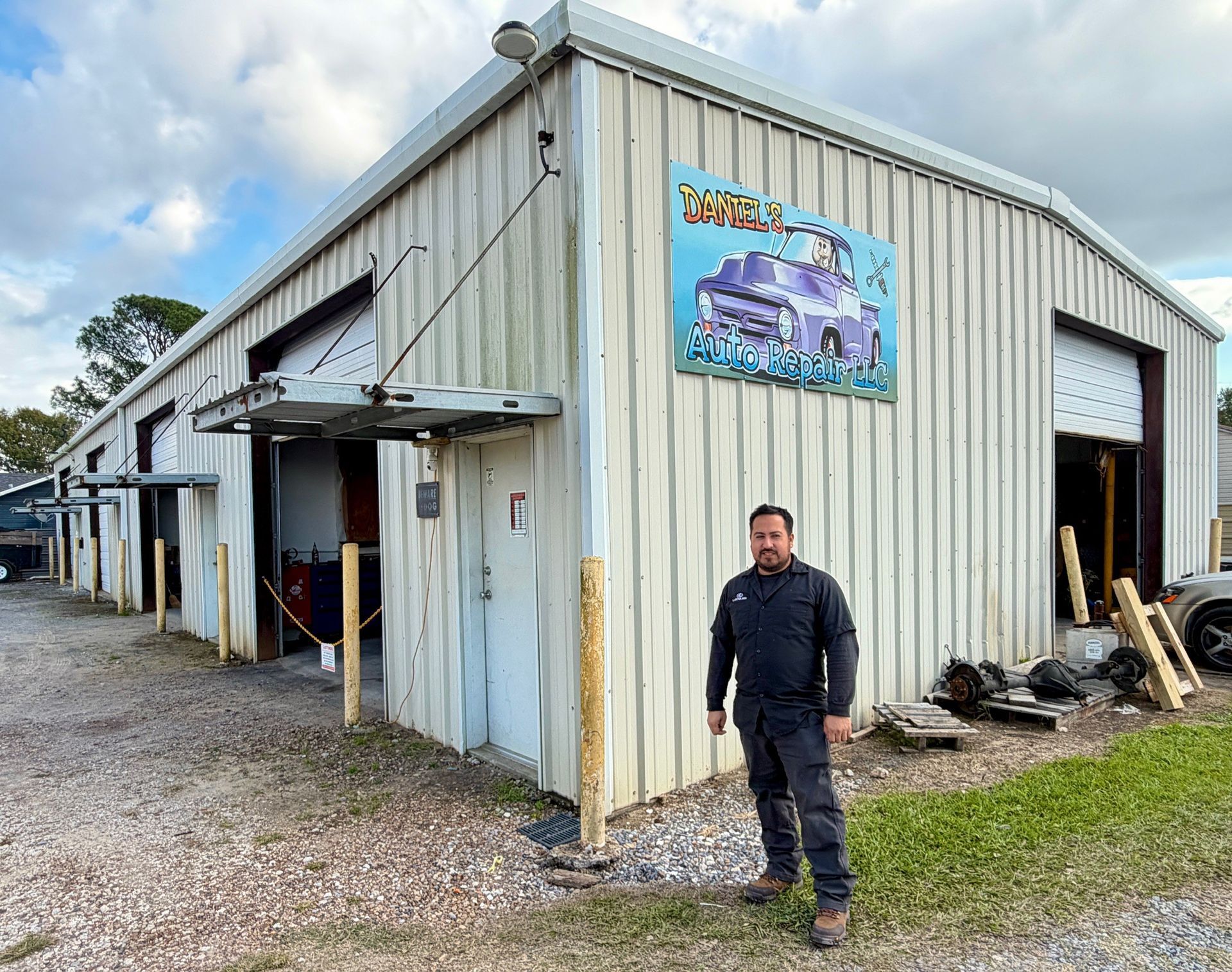 Man stands in front of a weathered metal garage. Sign reads 