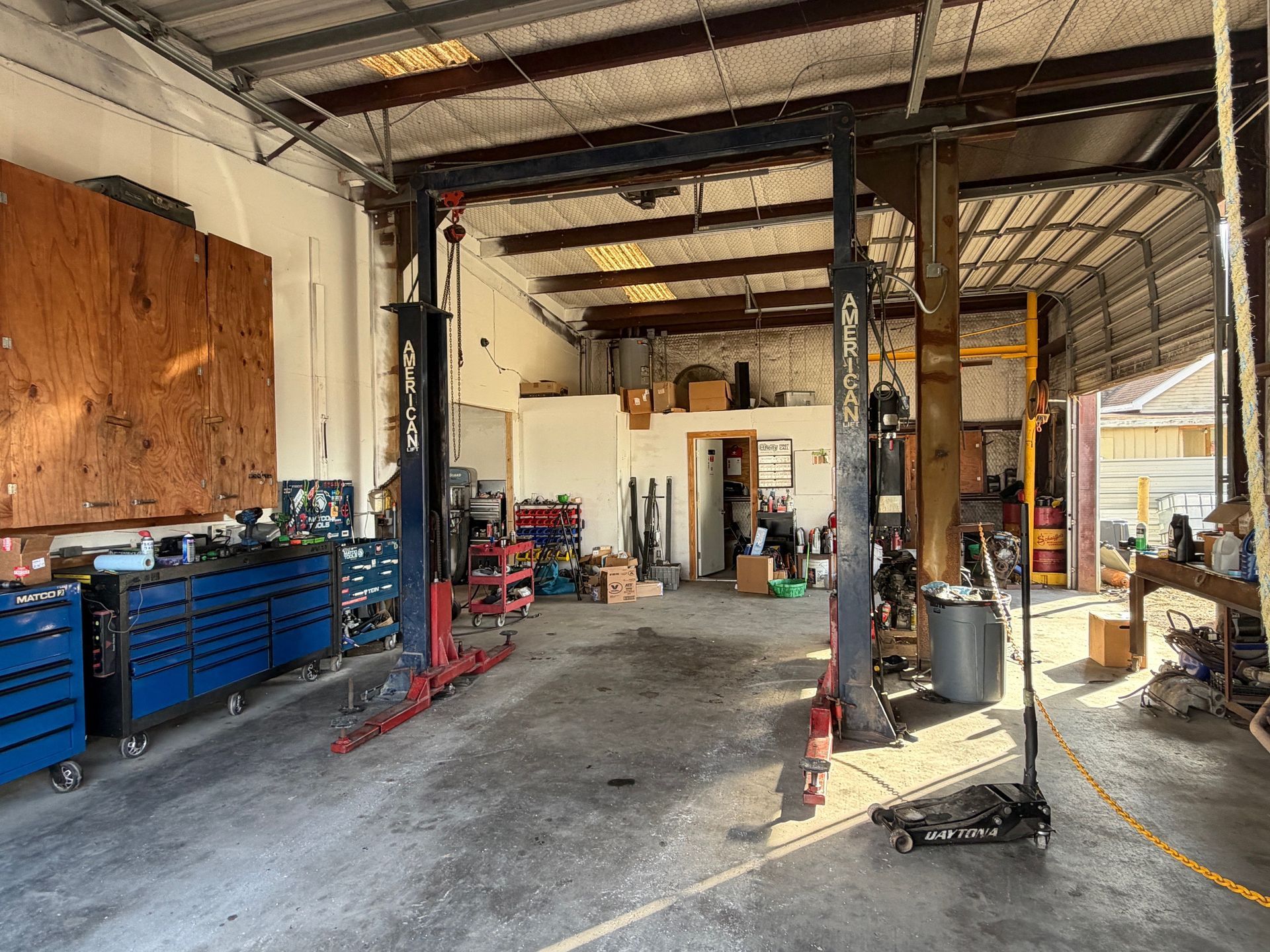 Auto repair shop interior with vehicle lift, tools, and work area.