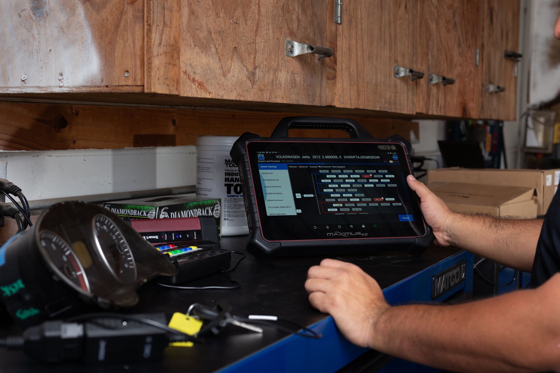 Person using a diagnostic tablet in a garage setting, working on a vehicle.