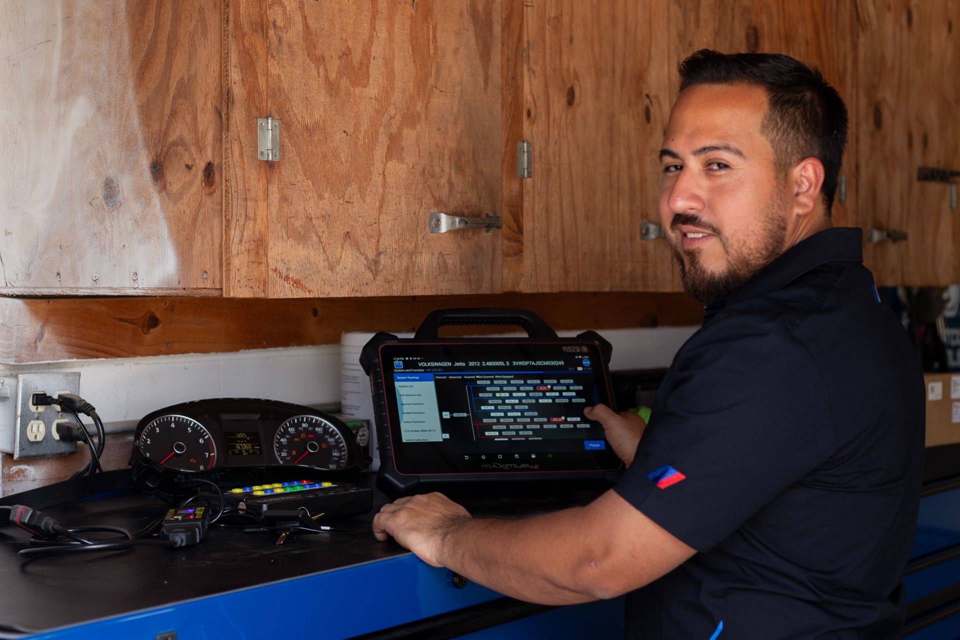 Mechanic using a diagnostic tablet in a garage, looking at the camera.