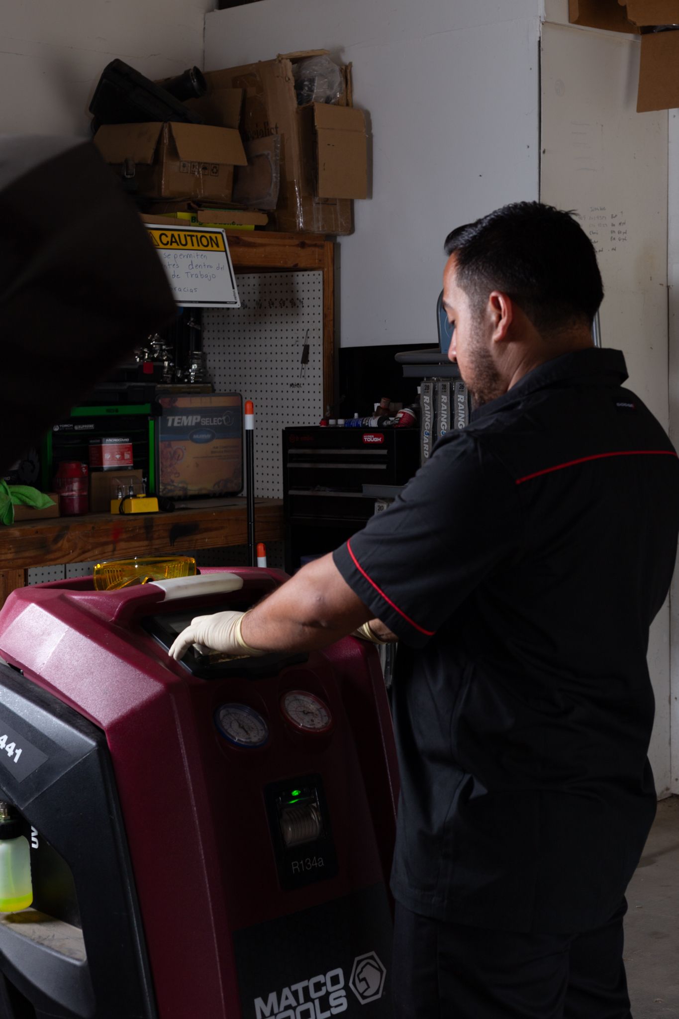 Mechanic operating a red and black Matco Tools machine in a garage.