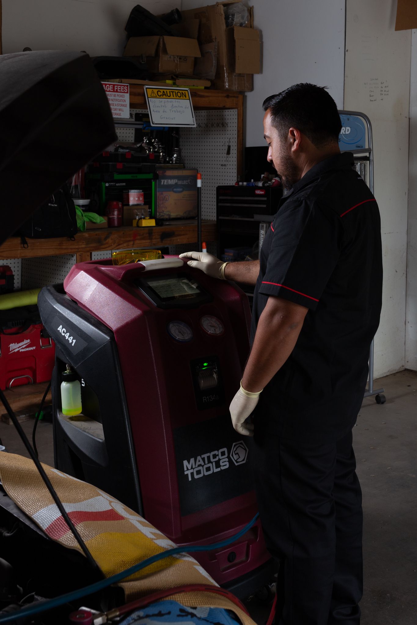 Mechanic in black uniform operating an AC machine in a garage.