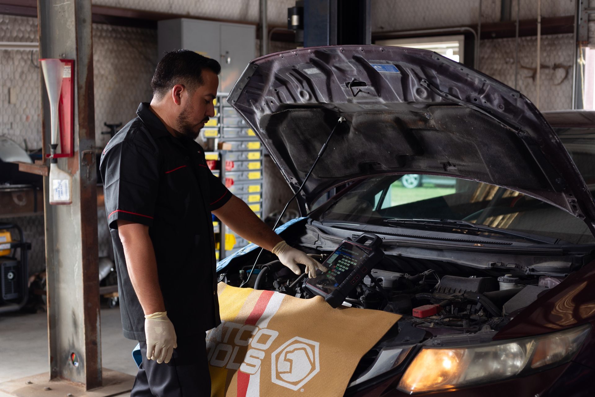Mechanic using a diagnostic tool on a car in a garage.