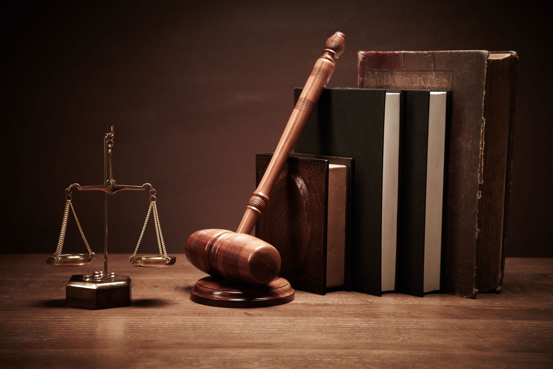 A wooden gavel , scales of justice , and books on a wooden table.