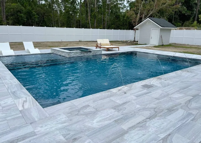 A rectangular pool with light gray tile surrounds; a spa sits in the top left, a white shed in the background.
