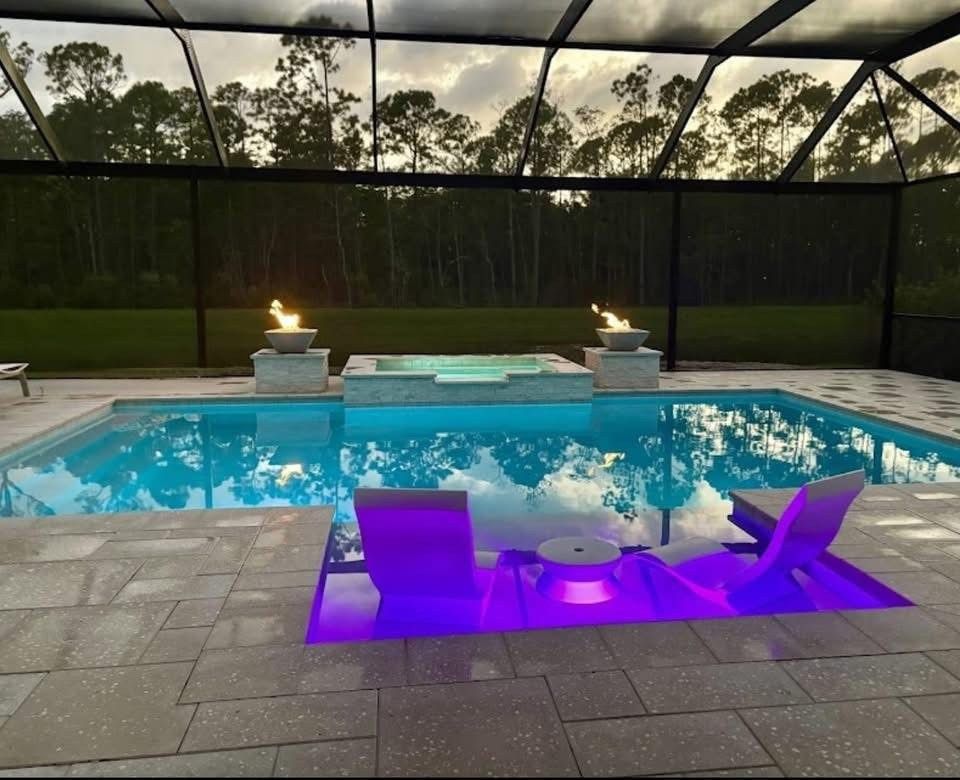 Swimming pool with attached spa, outdoor patio with seating, and screen enclosure.