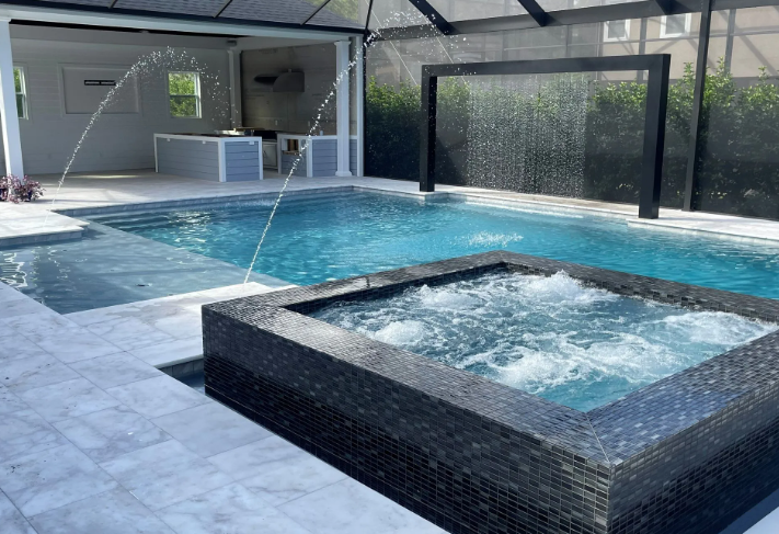 Swimming pool with a jacuzzi, waterfall, and outdoor kitchen.