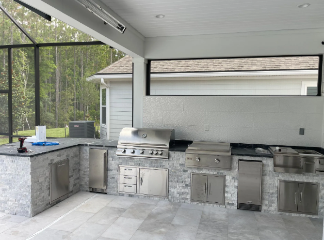 Outdoor kitchen with stainless steel appliances and gray stone accents.