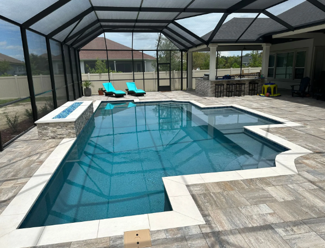 Pool with screened enclosure, tile deck, fire feature, lounge chairs, and an outdoor bar.