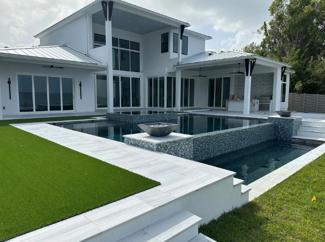 Modern white house with a pool and green lawn.