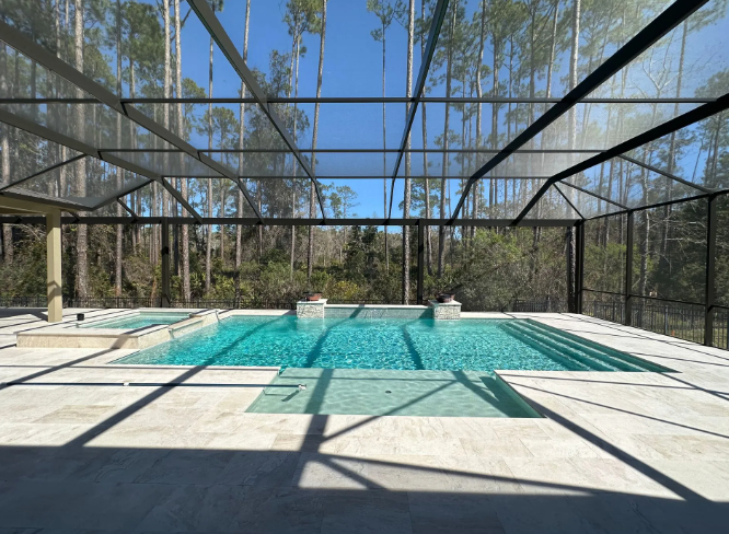 Pool with turquoise water inside a screened enclosure; trees in the background, blue sky overhead.