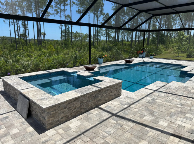 Pool and hot tub with blue water, surrounded by stone and screened enclosure.