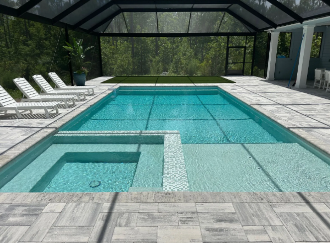 Pool enclosed in a screen structure; includes a hot tub, lounge chairs, and light-colored paving.