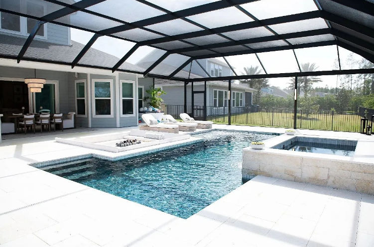 Pool area with screened enclosure, pool, hot tub, lounge chairs, and house in background.