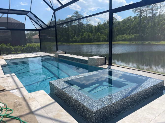 Pool and spa enclosure overlooking a lake, blue water, beige tiling, black screening.