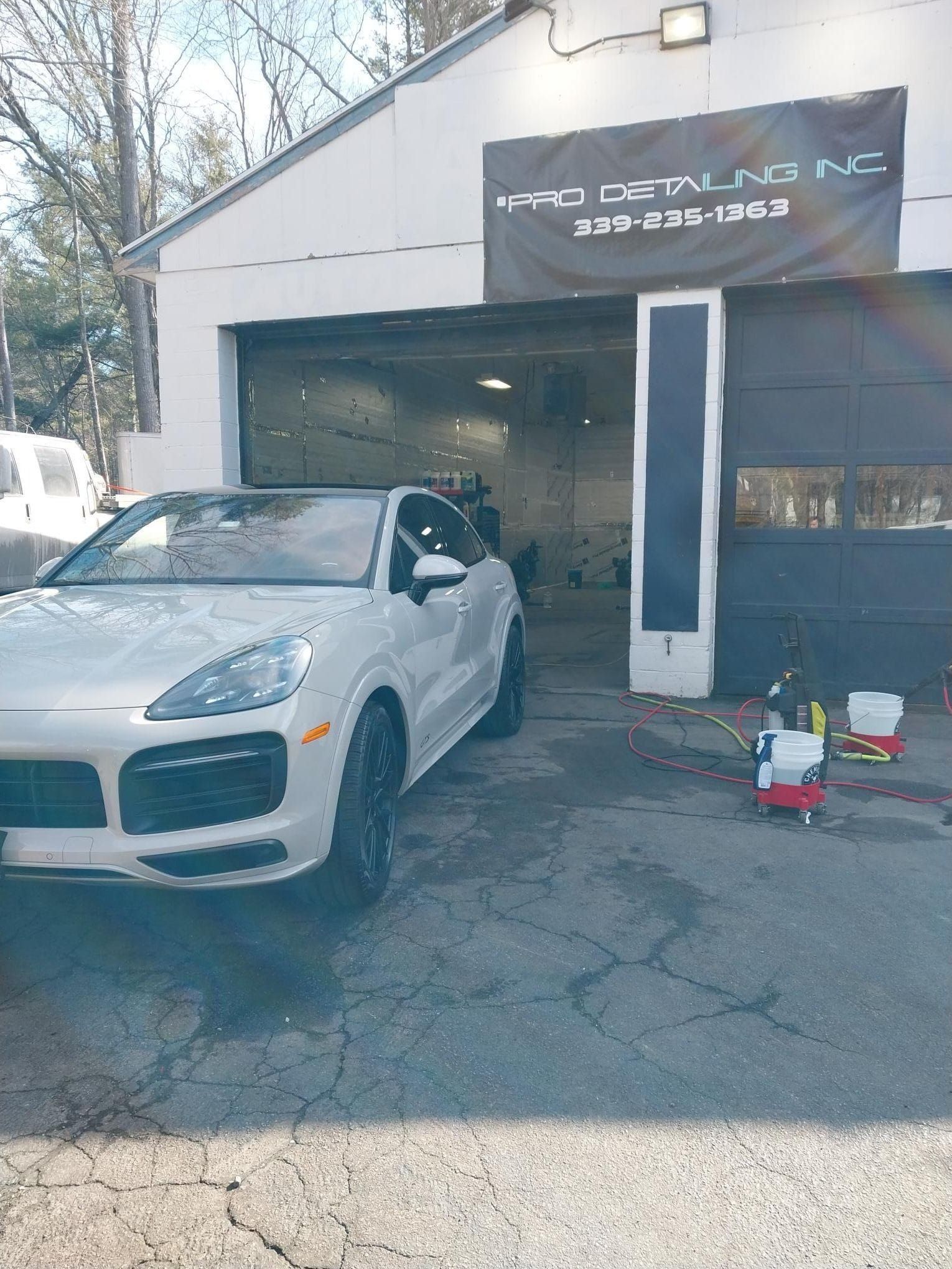 Gray Porsche SUV with black rims and red brake calipers, parked on wet pavement.
