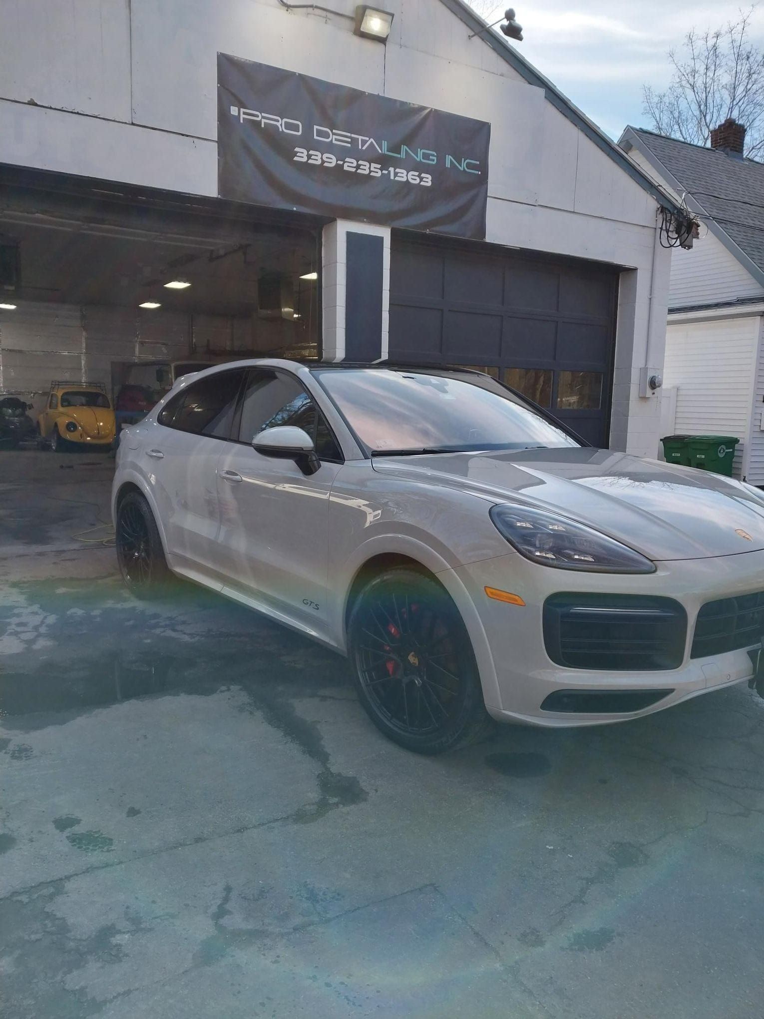 Gray Porsche SUV with black rims and red brake calipers, parked on wet pavement.