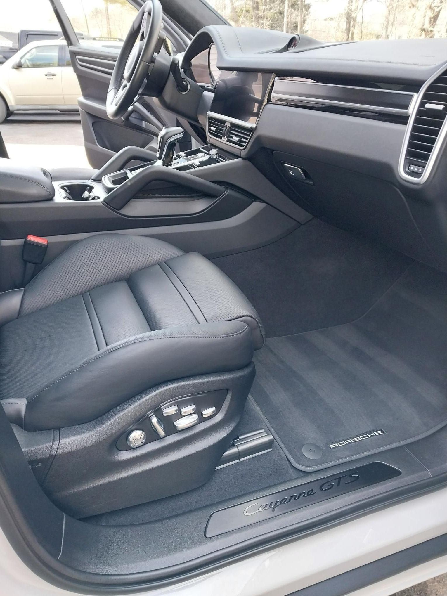 Interior of a black Porsche Cayenne GTS with black leather seat, floor mats, and dashboard.
