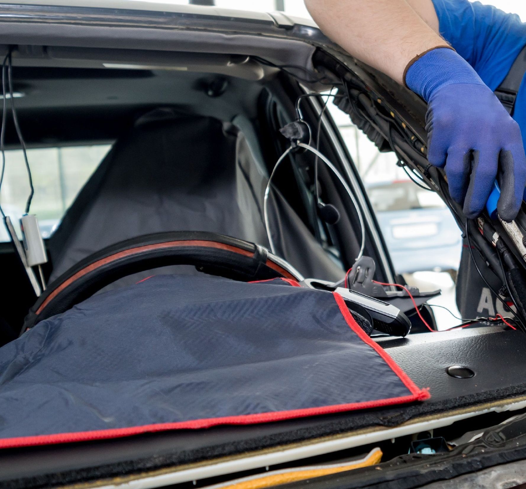 A man wearing blue gloves is working on a car windshield
