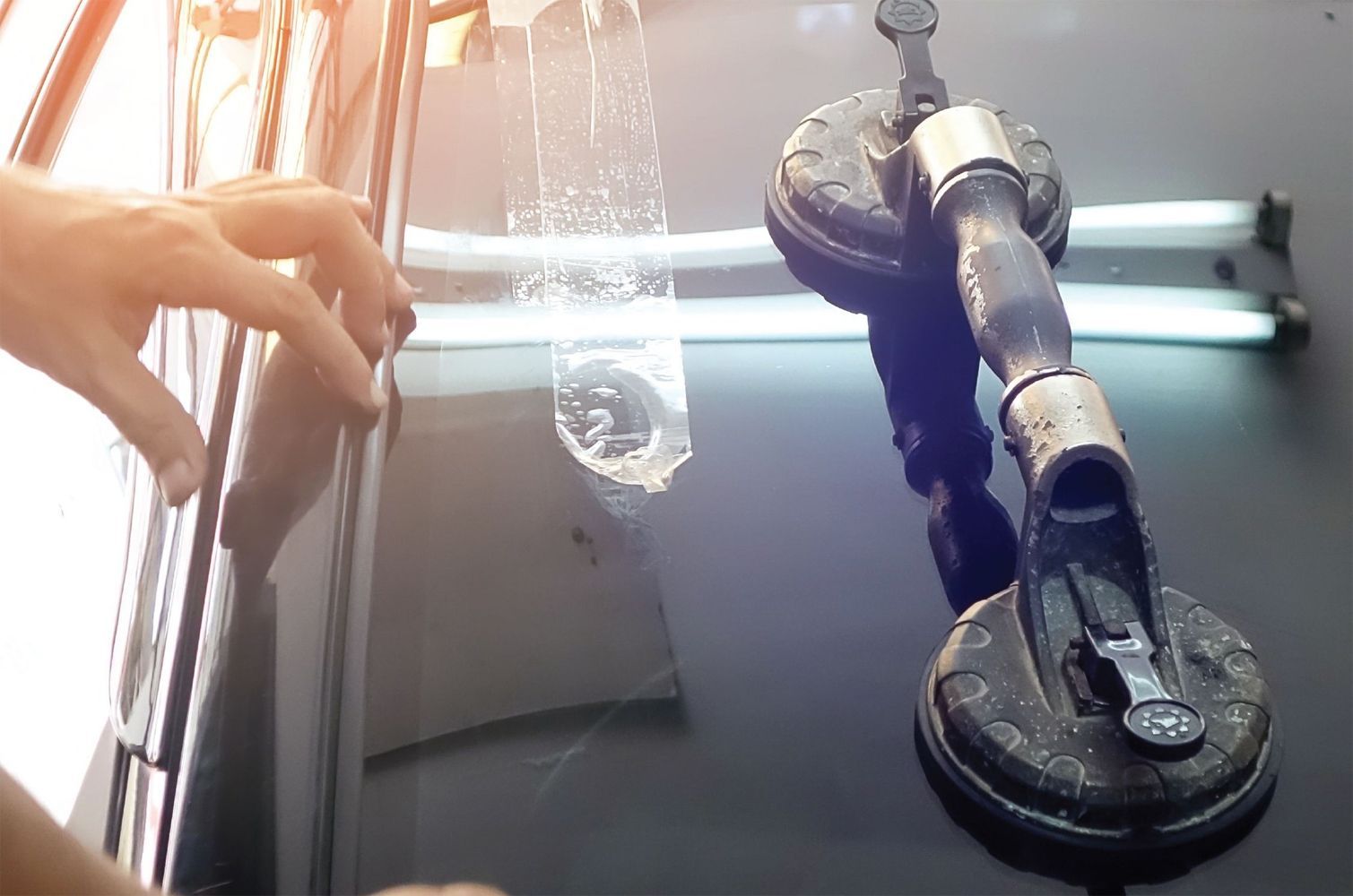 A person is fixing a windshield on a car with a suction cup.