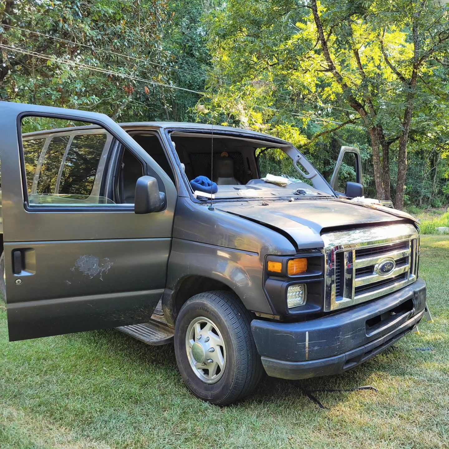 A black van is parked in the grass with its doors open.