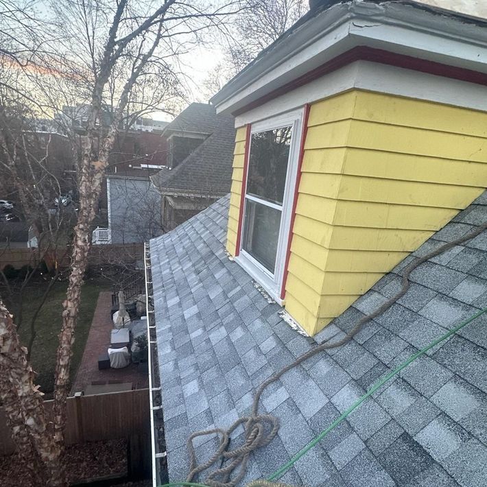 A house with a yellow siding and a window on the roof