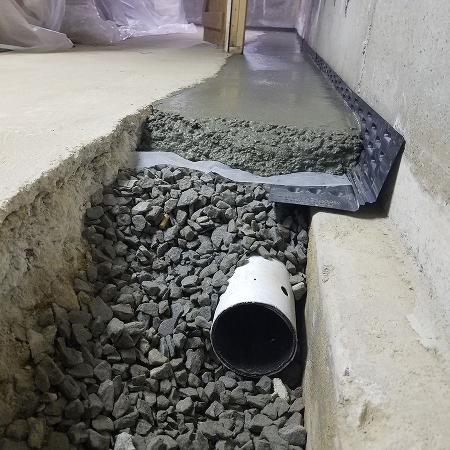 A white pipe is laying in a pile of gravel