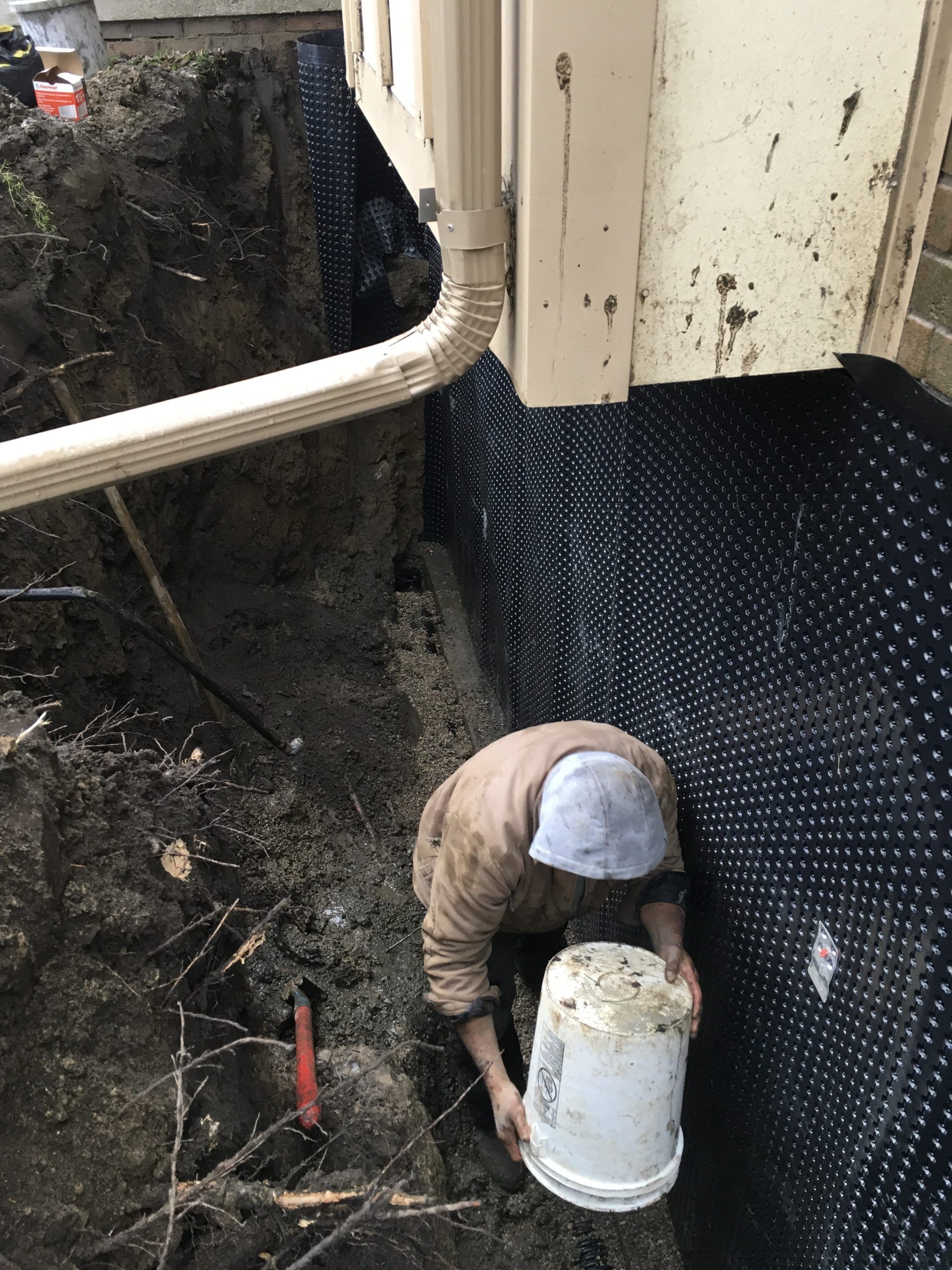 A man is digging a hole in the ground with a bucket.
