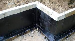 A corner of a concrete wall with a black coating on it.