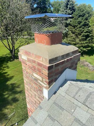 A brick chimney is sitting on top of a roof.