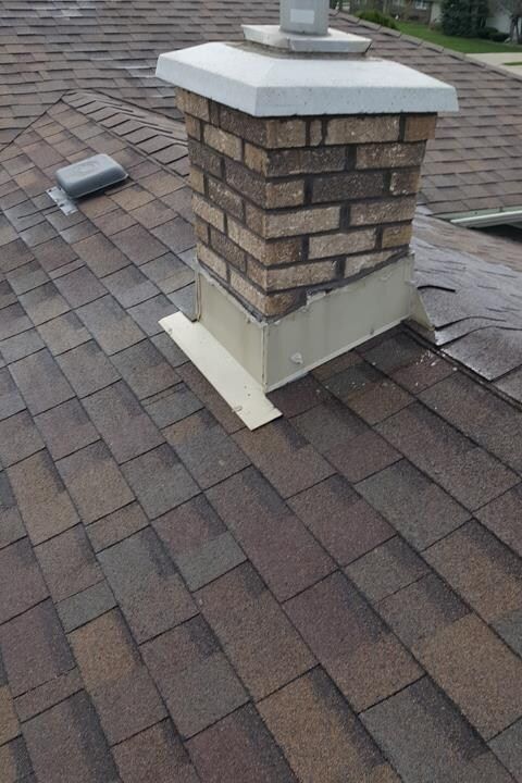 A brick chimney is sitting on top of a roof.