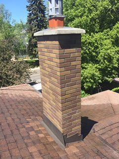 A brick chimney is sitting on top of a roof.