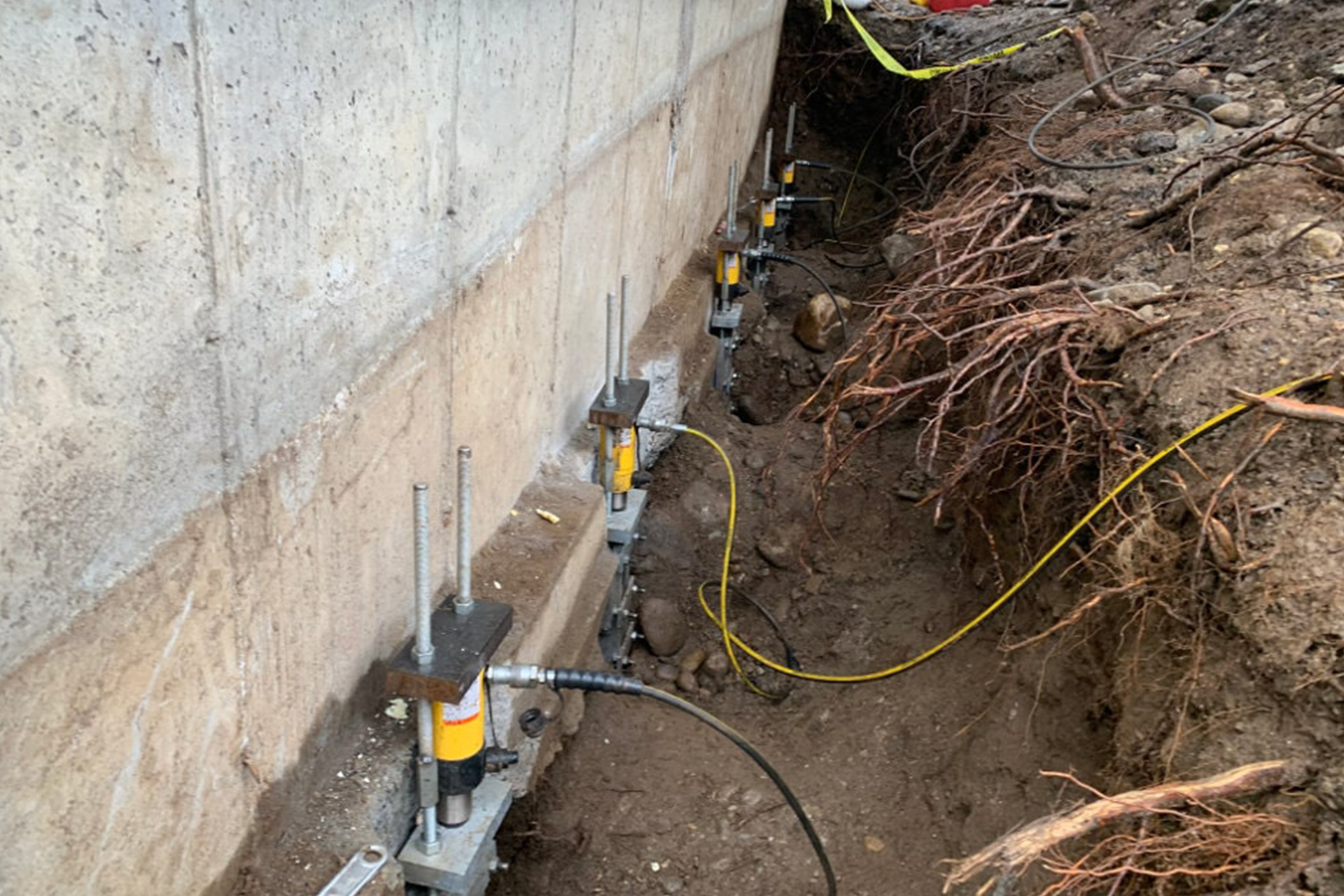 A concrete wall is being supported by hydraulic jacks.