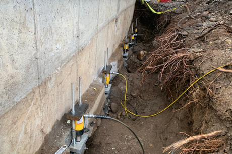 A concrete wall is being supported by hydraulic jacks.