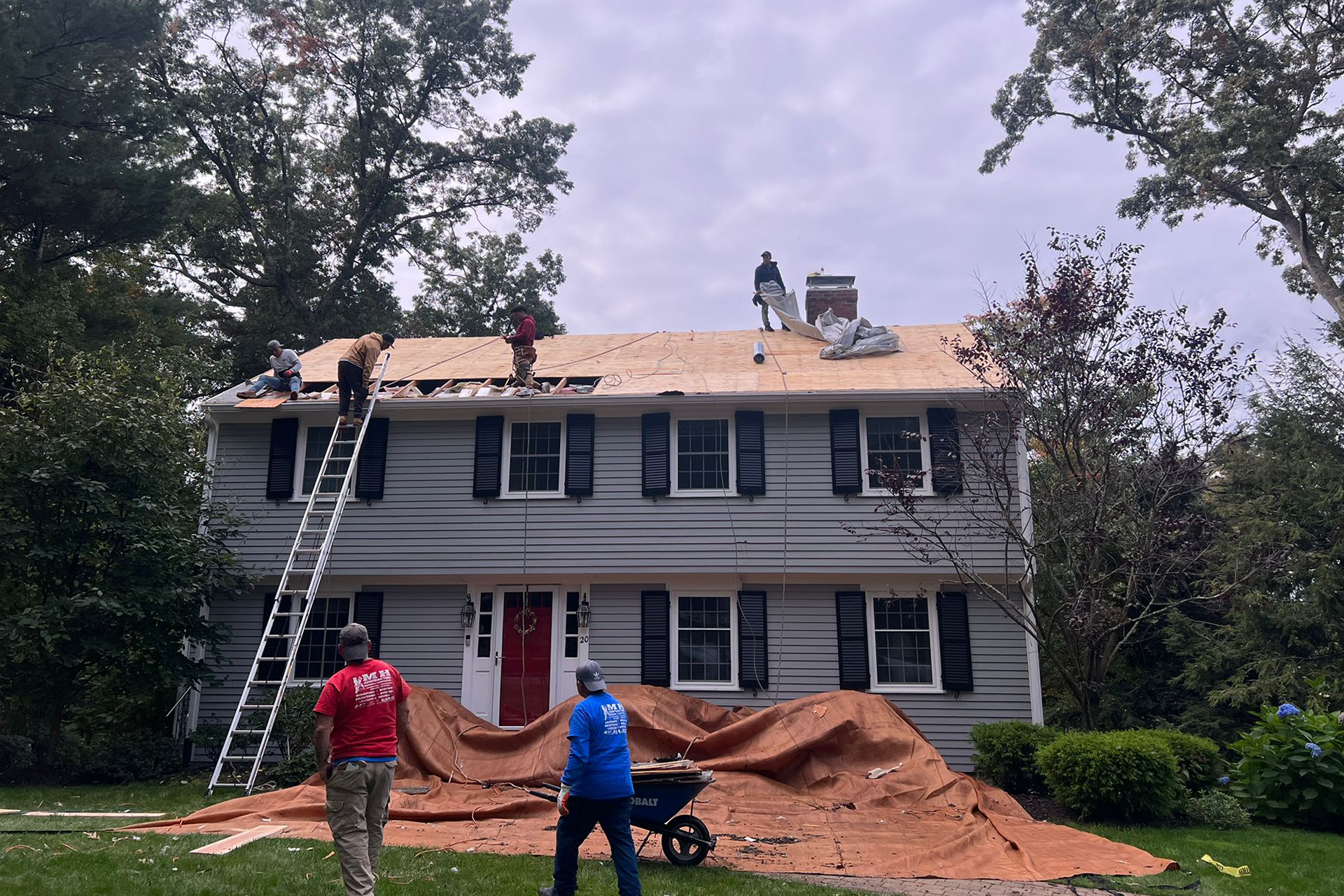 A group of people are working on the roof of a house.