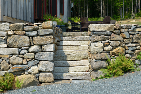 A stone wall with stairs leading up to a house.