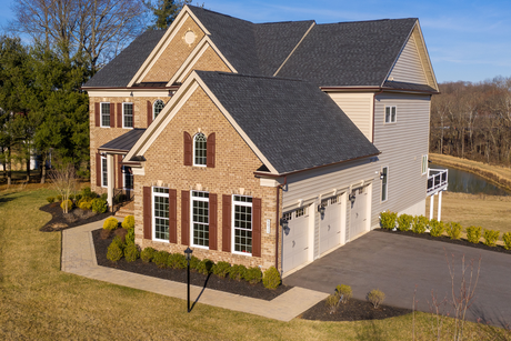 An aerial view of a large brick house with a garage and a driveway.