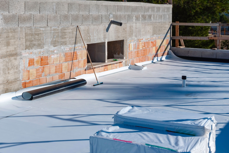 A white roof is being installed on a building under construction