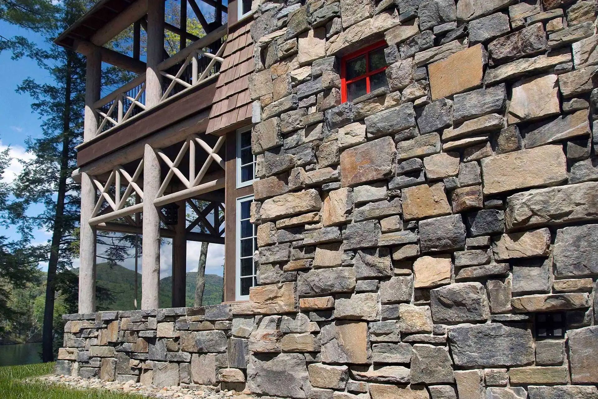 A large stone wall with a red window on the side of a building