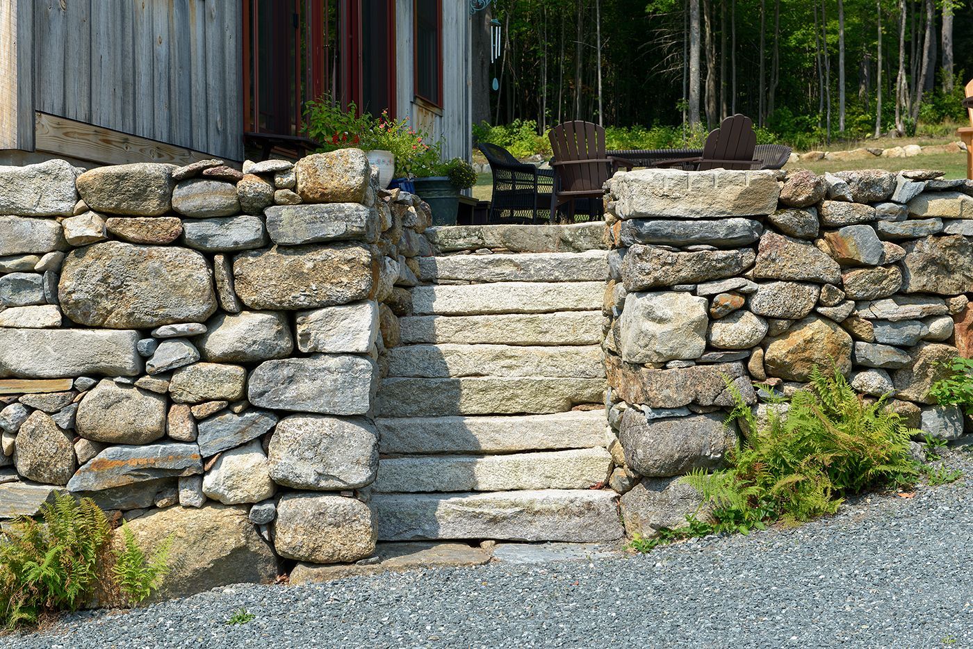 A stone wall with stairs leading up to a house.