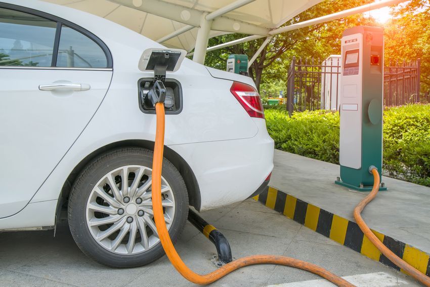 A white electric car is being charged at a charging station.