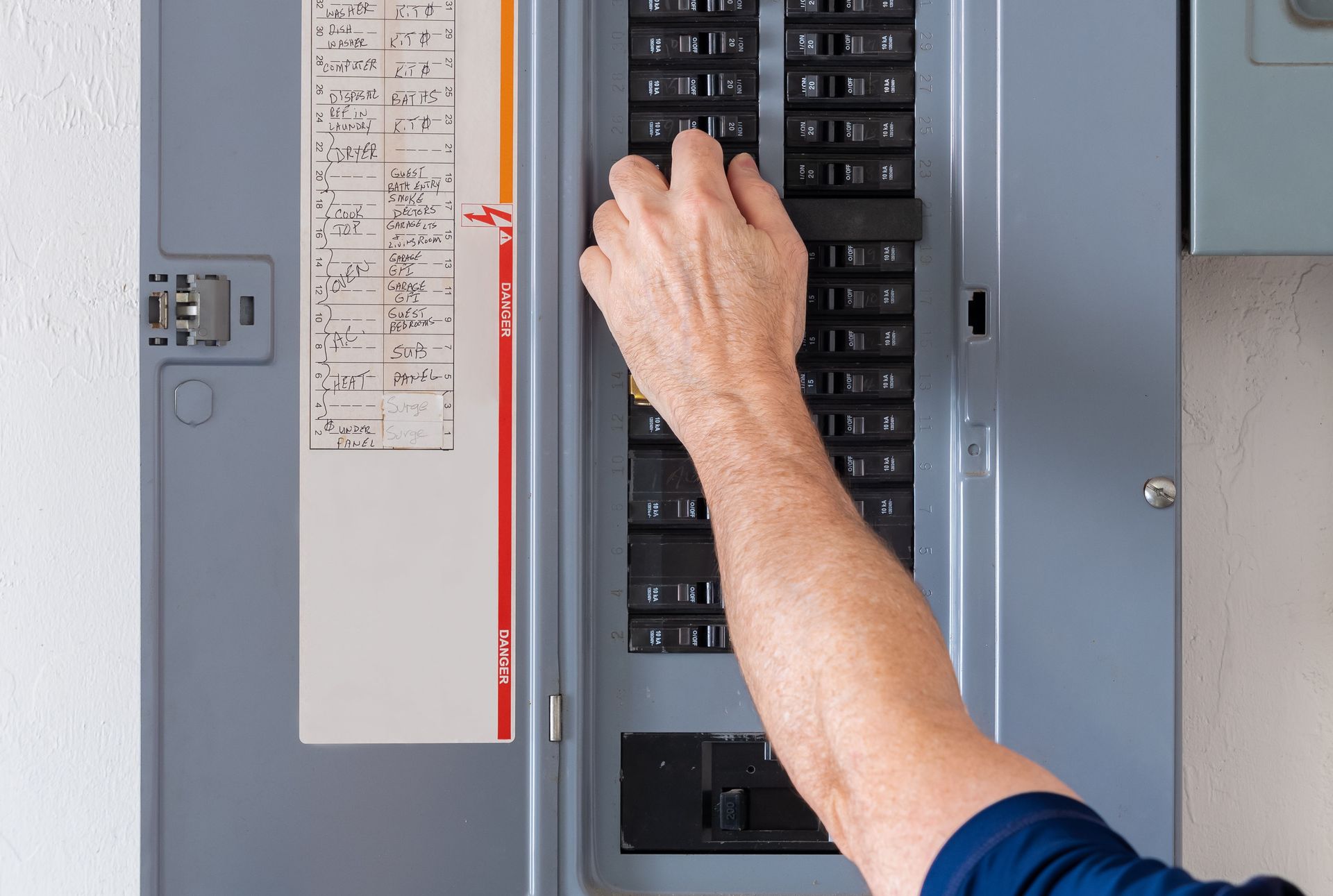A person is pressing a button on a electrical panel.